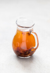 Compote of dried fruits, dates, apricots, cranberry, raisins in a glass jug on a light gray background