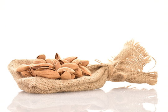 Unpeeled dried almonds on a jute bag, close-up, isolated on white.