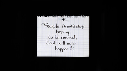 Hand written message on a ripped notebook sheet: People should stop hoping to be normal, that will never happen!!!