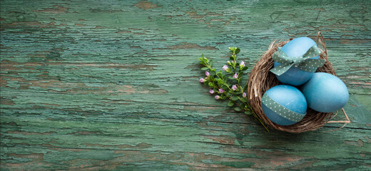 Pastel blue colored easter eggs on green shabby wood. Country style easter decoration with flowers....