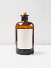 Medicine small glass bottle. Vintage bottle with wood cork. Container for homemade liquids, oils, mixtures. Mock up with a white label, studio shot. 
