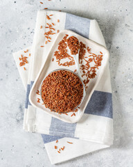 Red rice in a glass bowl on the light gray kitchen table. Red rice on a light background