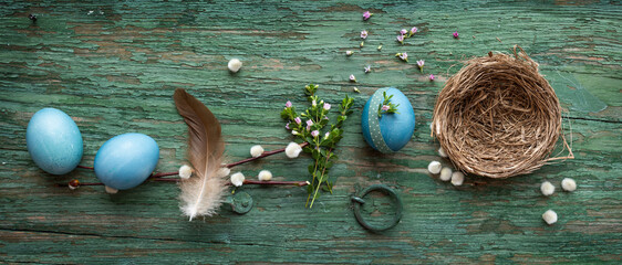 Pastel blue colored easter eggs on green shabby wood. Country style easter decoration with flowers...