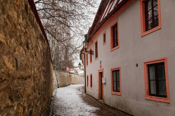 Fototapeta na wymiar Fascinating narrow picturesque street with baroque and renaissance historical buildings, snow in winter day, Novy svet, New World in vicinity of Hradcany, Prague, Czech Republic