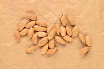 Unpeeled organic dried almonds, close-up, on brown paper, top view.