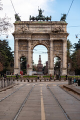 The Arco della Pace in Milan, in an afternoon with sun and clouds and a blue sky. In the background the Sforza castle