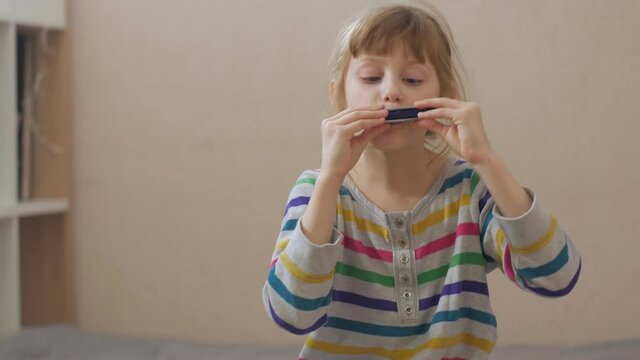 Funny girl playing harmonica home interior