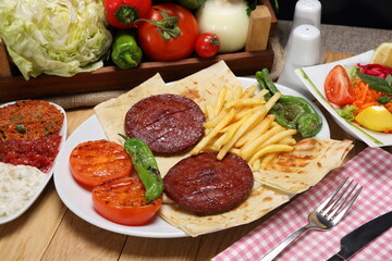 Grilled Turkish sudjuk plate served with bread, potatoes fries, girlled tomatoes and pepper