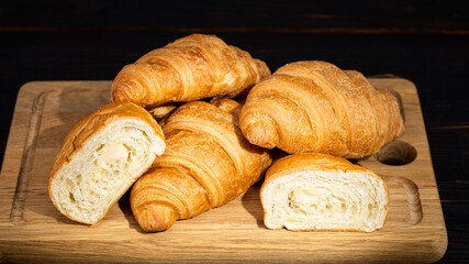 fresh croissants on wooden board on a dark background