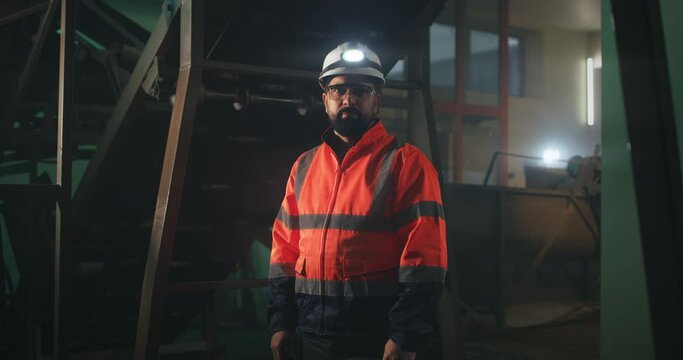 Male engineer looking at camera near machinery