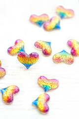 Fototapeta na wymiar rainbow glitter hearts on white background close up. colorful small shiny hearts, symbol of love. Valentine's Day, 14 february, romantic date concept
