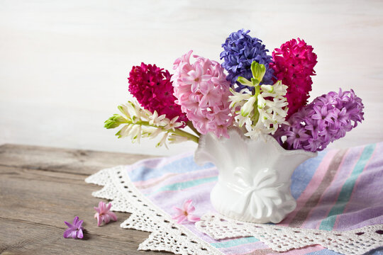 A bouquet of hyacinths in a vase on a wooden table.