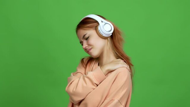 Teenager girl listening music with headphones with shoulder pain over isolated background
