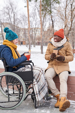 Young couple having a date in the park in winter day they talking and drinking hot coffee