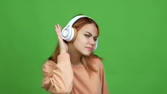 Teenager girl listening music with headphones listening something over isolated background