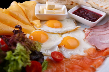 Breakfast fried eggs salad croutons bread cheese ham fish salmon on a white plate