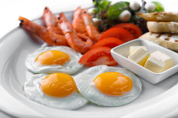 Breakfast fried eggs salad croutons bread butter greenland prawns on a white plate
