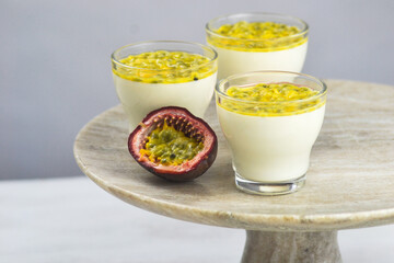 Italian dessert panna cotta in a glass cups with fresh passion fruits on a cake stand.