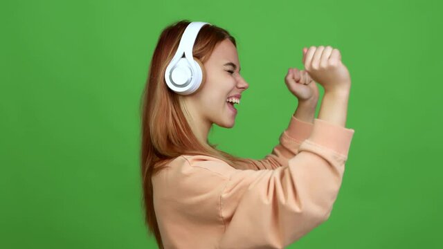 Teenager girl listening music with headphones celebrating a victory over isolated background