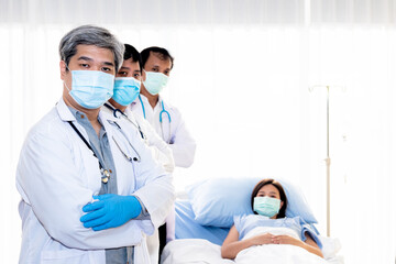 Professional doctor team of Asian man, wearing a surgical mask To prevent the spread of germs or virus, ready to care and treatment the patient, with blur patient woman background, health care concept