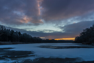 Sunrise on a frosty morning with a frozen lake.