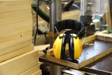 Ein Geh&ouml;rschutz zur Arbeitssicherheit liegt auf einer Maschine neben gestapelten Holzlatten