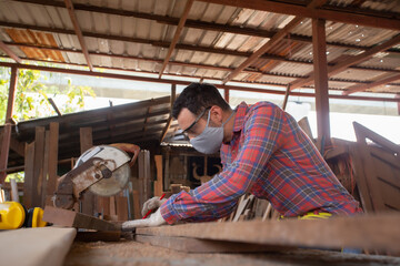Obraz na płótnie Canvas Skilled carpenter cutting a piece of wood in his woodwork workshop