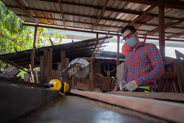 Skilled carpenter cutting a piece of wood in his woodwork workshop