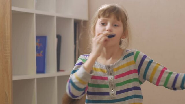 Happy girl playing harmonica home interior