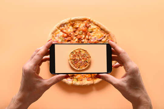 Woman hands takes photography of Italian vegan pizza with tomato, mozzarella, sauce. View from above. Smartphone photo for social networks post.