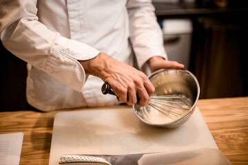 Close-up of male chef's hands mixing ingredients in steel bowl