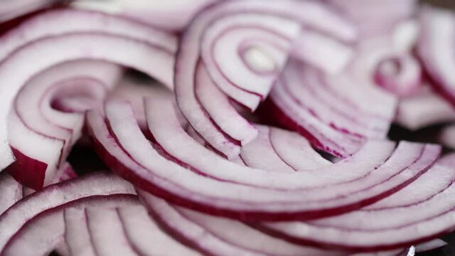 sliced fresh red onion pieces close up motion from left to right, healthy food preparation