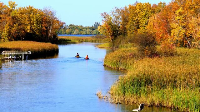 Mississippi River and two canoes head north toward Bemidji Minnesota near highway 2 with zoom in. Beautiful autumn colors in the trees along the river, a few miles from the source at Lake Itasca.