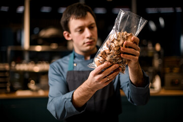 close-up of transparent bag with sliced mushrooms in the hands of male chef