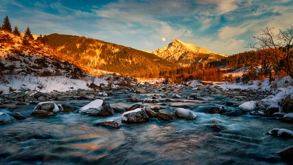 Krivan peak with the moon in full over a mountain river in High Tatras