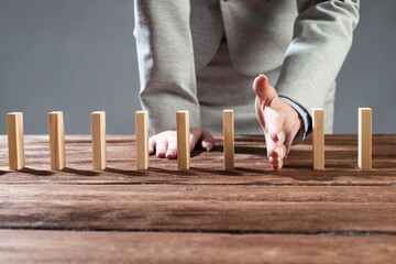 Businesswoman protecting dominoes from falling