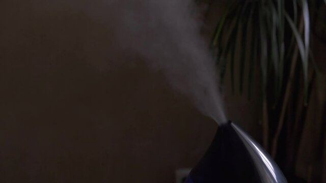 Steam from a modern air humidifier in dark room. Close-up, no people.