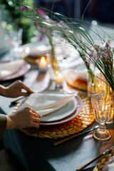 Decorator girl serves the table. The process of preparing a linen napkin from a cloth and serving on a plate. View from above. Braided cymbal hoop.