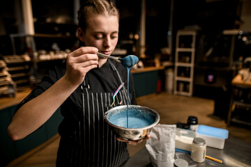 woman chef holds bowl with blue sauce and mixes and pours it with spoon
