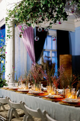Decorated table ready for dinner. Beautifully decorated table set with flowers, candles, plates and serviettes for wedding or another event in the restaurant. Red and rose flowers on grass.