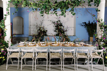 Obraz premium Table decorated with genista flowers and bergrass. Serving with wicker coasters for plates, napkins, burning candles and glasses. Decorations and table for wedding and dinner parties.