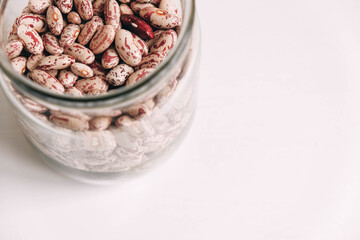 Raw beans in a glass jar on a white table background. Top view. Copy, empty space for text
