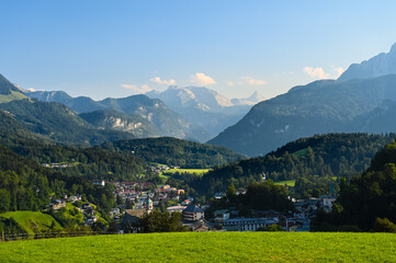 Amazing alpine mountain panorama with the city of Berchtesgaden, Germany and the huge Watzmann mountain in the background under a clear blue sky.