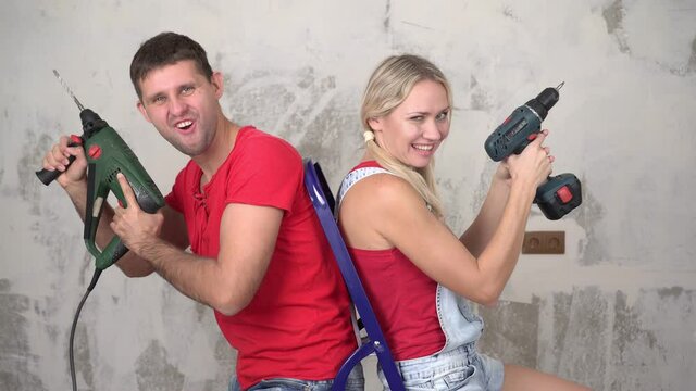 Positive young married couple with tools on the background of home renovation