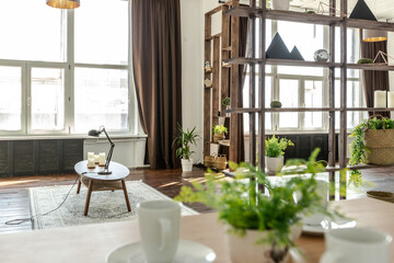 spacious studio apartment decorated with wood and white. Minimalist design with huge windows in the sunlight. kitchen area and living area