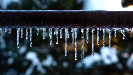 Many small icicles in the winter. Icicles hanging from a brown pipe. Frozen water and metal surface, winter time concept