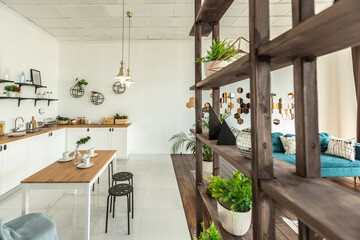 spacious studio apartment decorated with wood and white. Minimalist design with huge windows in the sunlight. kitchen area and living area