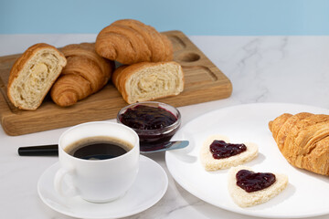 fresh croissants with jam and coffee on light background