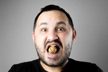 a man tries to crack a nut with his teeth. the concept of a complex problem or strong teeth