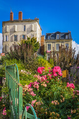 Fototapeta na wymiar flowery garden with in the background typical early 20th century houses in the historic center of Nevers, located in Burgundy, France